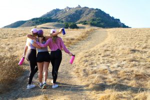 girls hiking with hats and water bottles